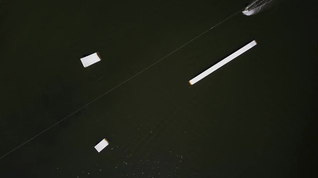 Aerial shot of a cableway in a lake with a wakeboarder grinding and rotating on a funbox