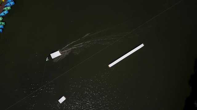 Aerial shot of a cableway in a lake with a wakeboarder grinding and rotating on a funbox