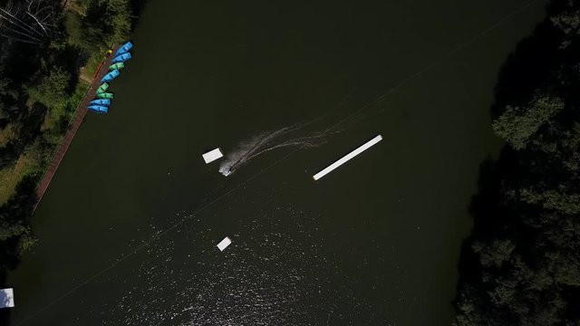 Aerial shot of a cableway in a lake with a wakeboarder grinding and rotating on a funbox