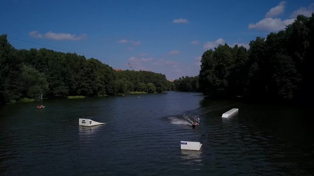 Aerial shot of a cableway in a lake with a wakeboarder grinding and rotating on a funbox