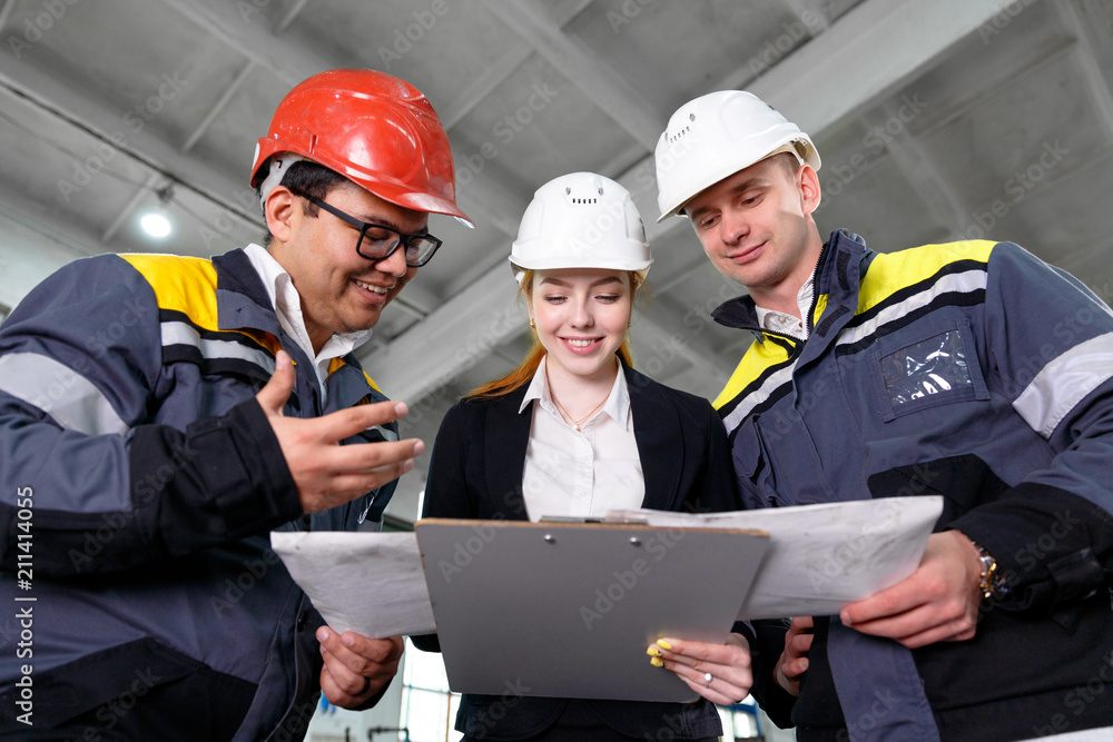 Poster young engineers and workers discuss technical documentation. work in a modern factory. girl engineer