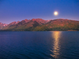 Nocturnal landscape of moon reflecting in Jackson Lake at night in Grand Teton National Park, Wyoming, United States of America in summer time and camping.