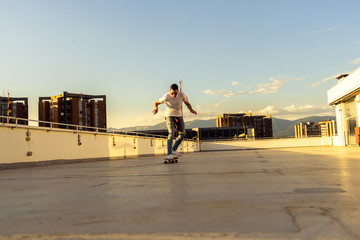 Adult guy having fun with skateboard on the rooftop. Young and careless having fun concept.