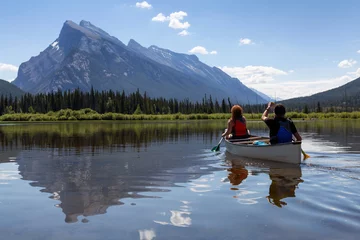 Poster Een stel avontuurlijke vrienden is aan het kanoën in een meer omringd door de Canadian Mountains. Genomen in Vermilion Lakes, Banff, Alberta, Canada. © edb3_16