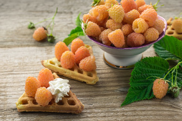 Yellow raspberries in a bowl and homemade waffles with raspberries.