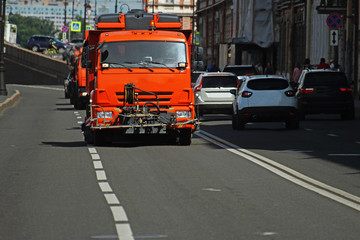 orange truck driving on the road in the city