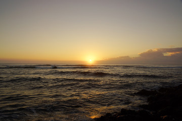 Sunrise over the ocean with waves crashing along shore