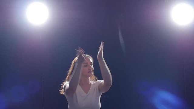 Young woman dancing on a black background