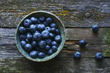 Delicious raw organic fresh blueberries in bowl on wooden table top view 