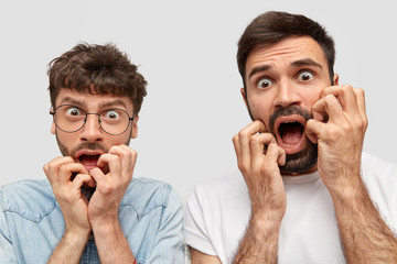 Frightened two men have scared expressions, look nervously, notice terrible accident on road, react...