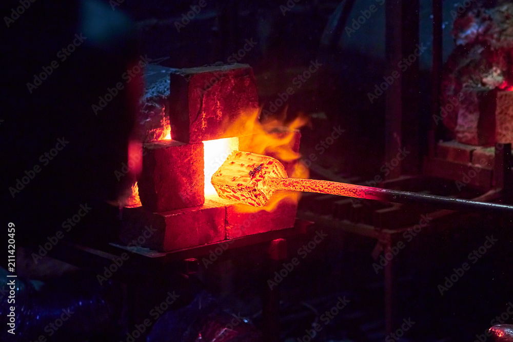 Wall mural hot item is inserted into the blacksmith's forge from which the tongues of flame. concept: blacksmit