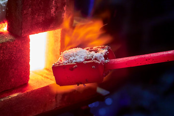 Hot item is inserted into the blacksmith's forge from which the tongues of flame. Concept: blacksmithing, forge