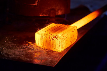 Glowing iron ingot on the table. Hot metal workpiece for the manufacture of Damascus steel.