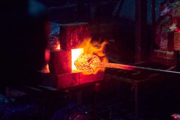 Hot item is inserted into the blacksmith's forge from which the tongues of flame. Concept:...