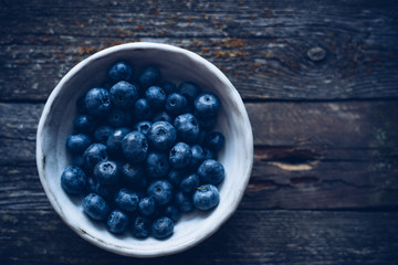 Delicious raw healthy organic blueberry in bowl on wooden table top view 