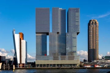 Fotobehang Stadsgezicht van Rotterdam met moderne wolkenkrabbergebouwen in het financiële district en het havengebied van de Nederlandse stad © Maarten Zeehandelaar