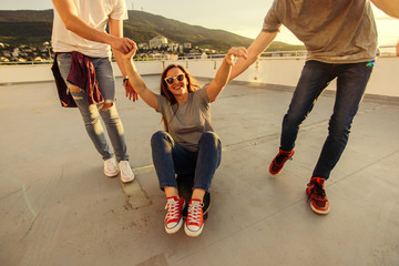 Portrait of adult friends while driving skateboard on the terrace. Young and careless friends having fun concept.