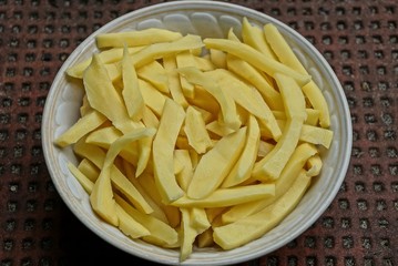 raw pieces of potatoes in a white plate on a table