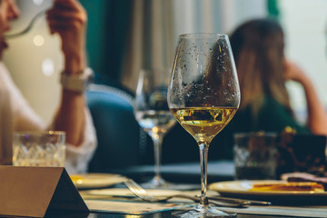 an unfinished glass of wine and a bored woman