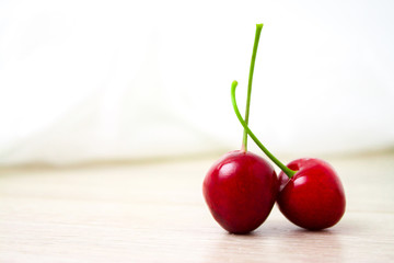 two Cherries Close-up. Cherry on wood and white background. Copyspace - healthy eating and food concept
