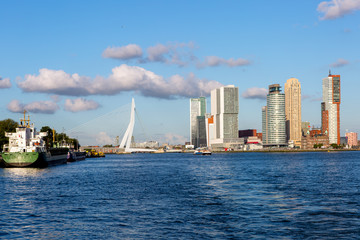 Fototapeta na wymiar Cityscape of Rotterdam with blue sky and clouds hanging over seen from the river Maas