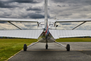 Symmetrical rear view of Cessna 172 Skyhawk 2 airplane on a runway with dramatic sky background. - obrazy, fototapety, plakaty