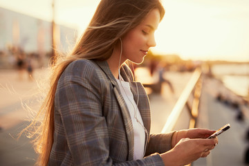 Pretty girl talk on her phone with sunset background