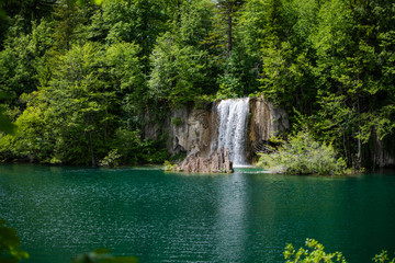 Fototapeta na wymiar View of some of the beautiful lakes of the national park and as the protagonist of the photo a waterfall with a great torrent of water that falls with force. Photograph taken in the Plitvice, Croatia.