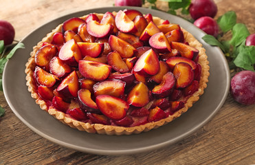 Delicious pie with plums on table