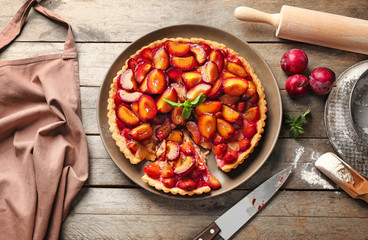 Delicious pie with plums on table