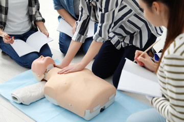 Group of people practicing CPR on mannequin at first aid class