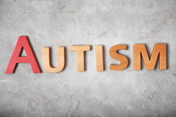 Word AUTISM on grey background, top view
