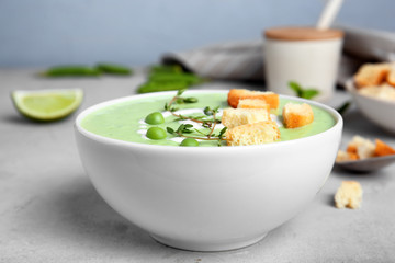 Green pea soup with croutons in bowl on table