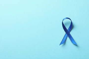 Blue ribbon on color background, top view. Cancer awareness