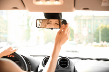 Young woman adjusting rearview mirror in car