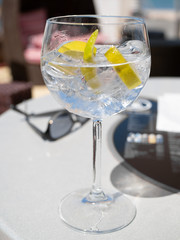 Glass of gin and tonic with lemon and ice cubes.