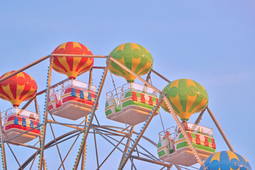 Fototapeta premium Multicolored booths of a ferris wheel over a blue sky background with a sunny day. Seafront in Bulgaria, Golden Sands.