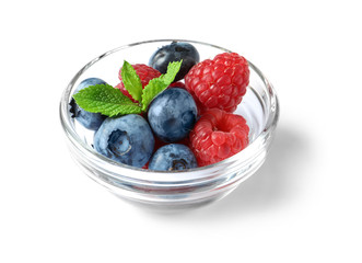 Bowl with raspberries and blueberries on white background