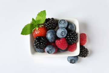Bowl with raspberries and different berries on white background