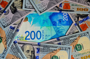 One new banknote of 200 Israeli shekels and a lot of bills of $ 100. Top view, background.