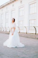 Obraz premium Happy young bride in flowing white dress enjoying herself outdoors