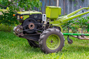 Obraz premium motor-block with green trailer. Development of traditional agricultural equipment and farming concept