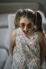Little girl with sunglasses at home