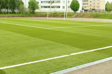 Artificial turf on the football field. Soccer field at the school stadium in the city. Background.