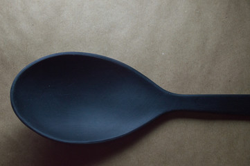 Colher de plástico para preparo de refeição na cor preta isolada em fundo marrom