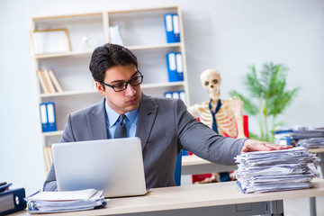 Naklejka premium Businessman working with skeleton in office