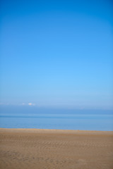 Fototapeta na wymiar The background texture desert beach. A cloudless sky and sand