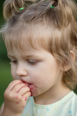 little girl eats cherry in the garden