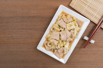 top view of stir fried pork with cabbage and oyster sauce in a plate on wooden table. asian hommade style food concept.