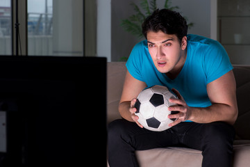 Young man watching football late at night